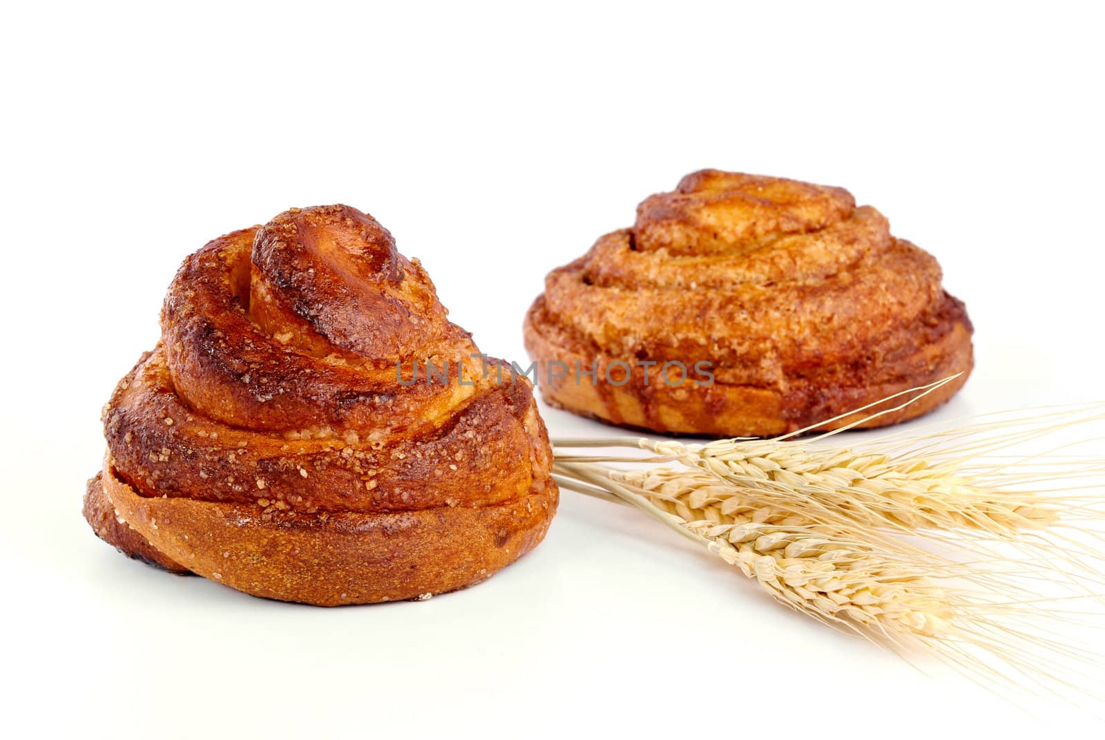 Cinnamon rolls with ear of wheat closeup on a white background