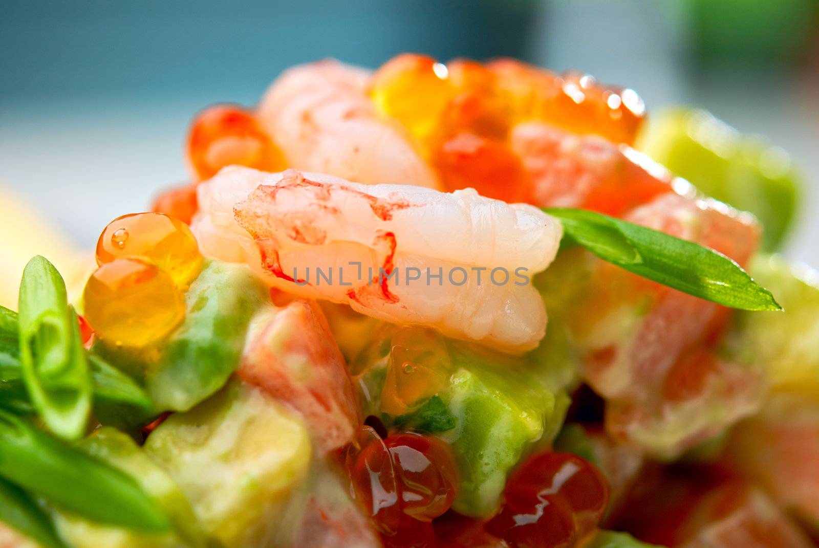 Salad of shrimps, avocado and herbs served with soft caviar. Macro, small depth of field. Blurry background.