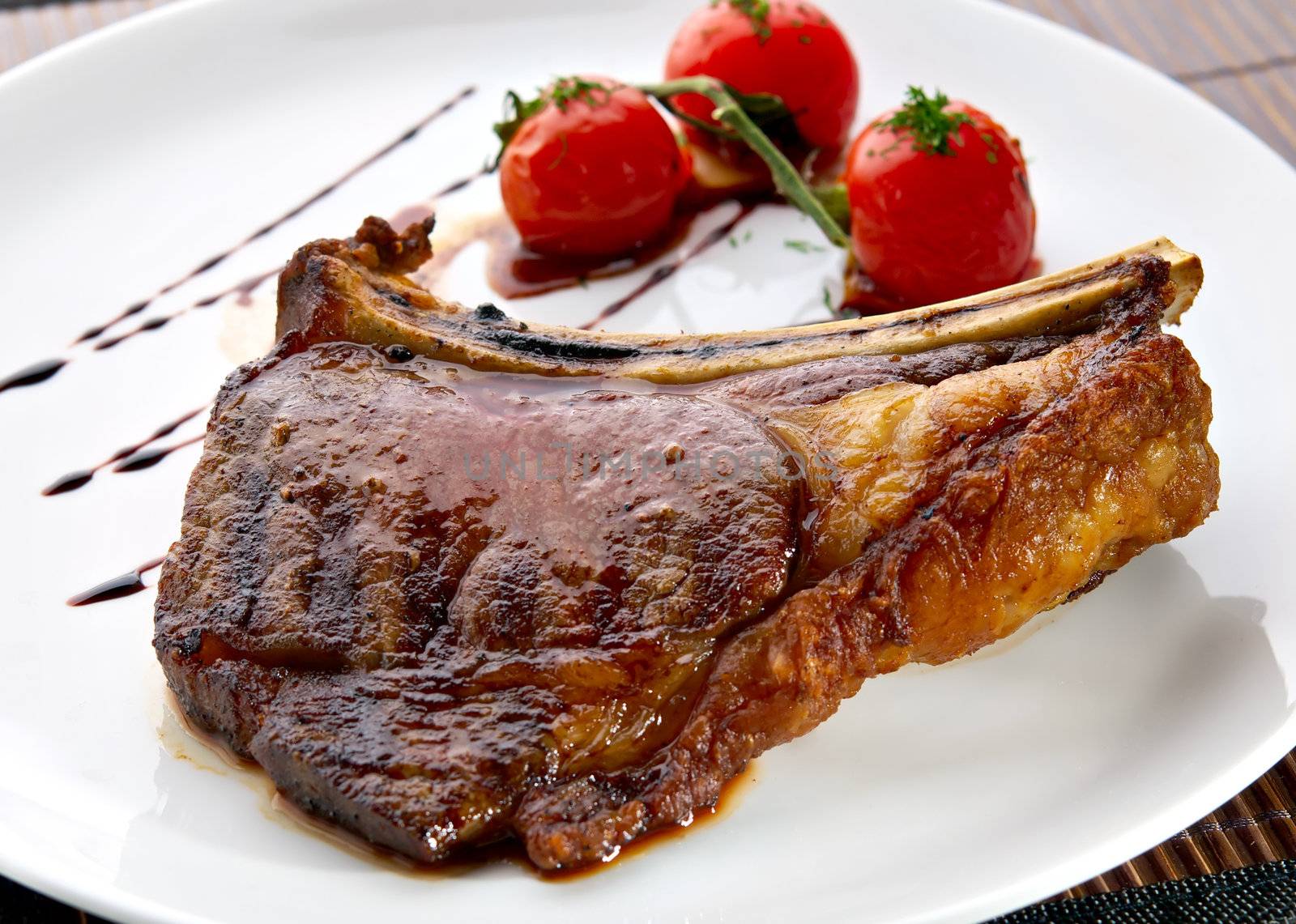 Grilled meat ribs on white plate with tomatoes by kirs-ua