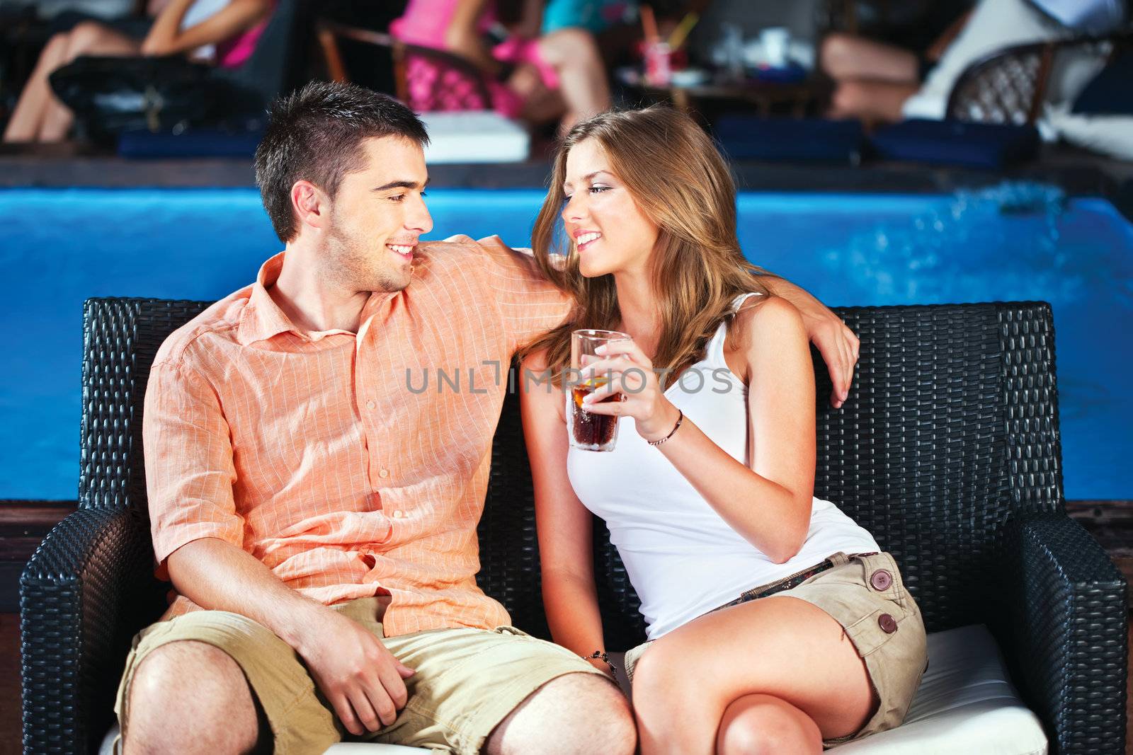 young couple outdoor near swimming pool on summer evening