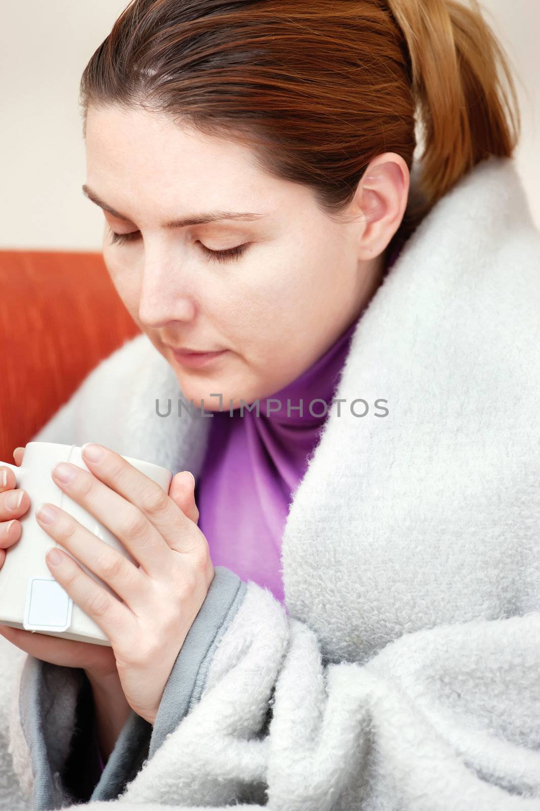 A young sick woman with a cup of tea in her hand