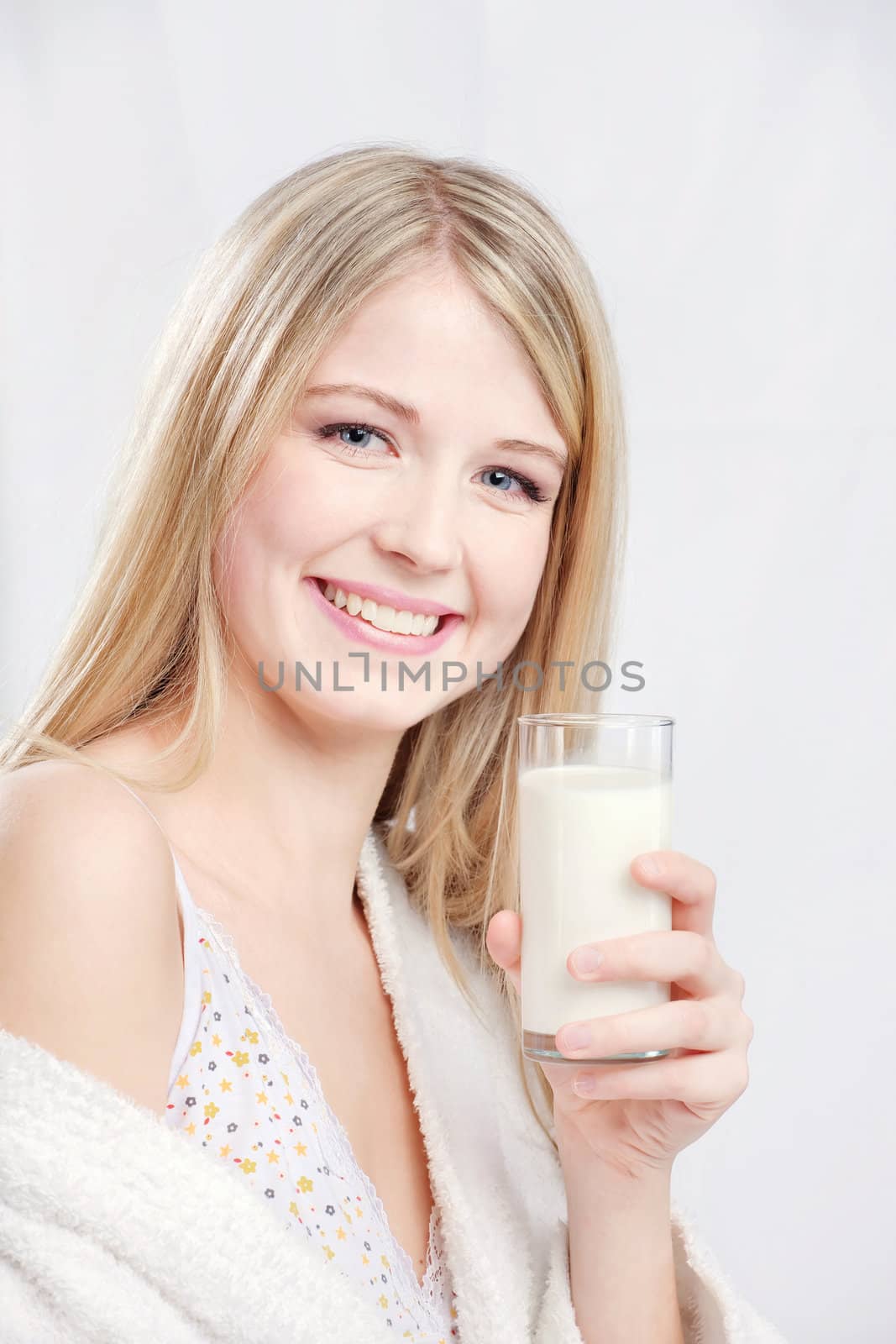 Smiling blond hair woman holding glass of milk