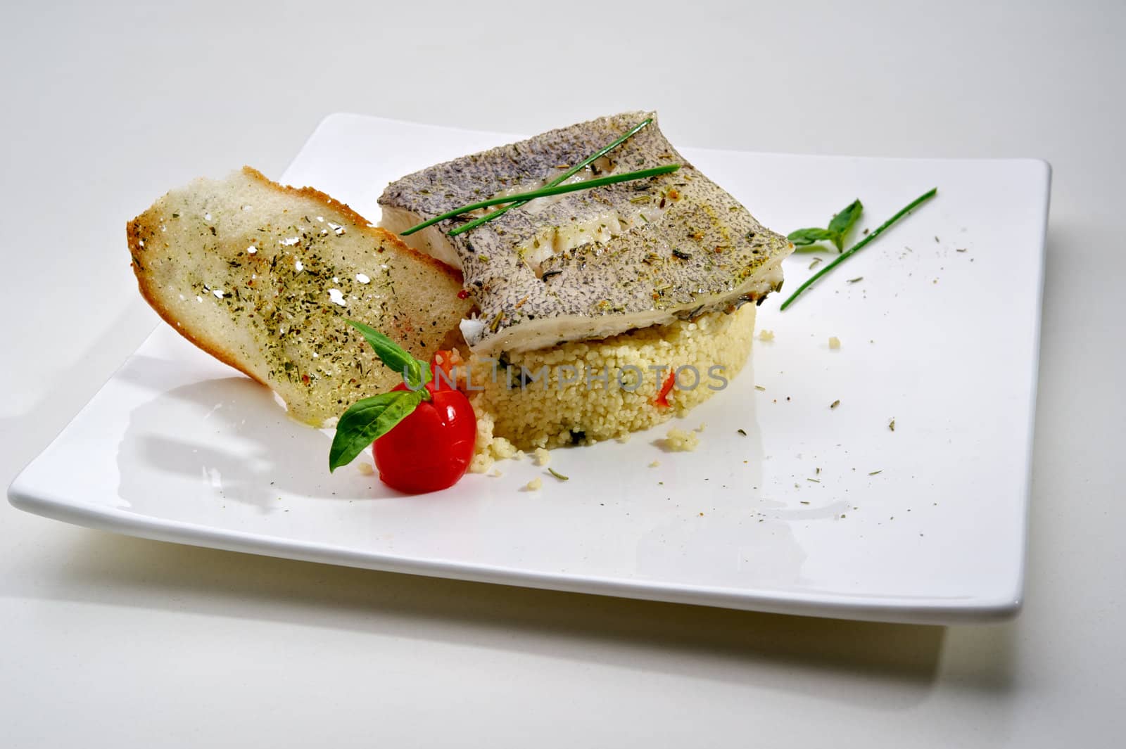 Pike-perch fillet garnished with vegetables and toast, served on white plate