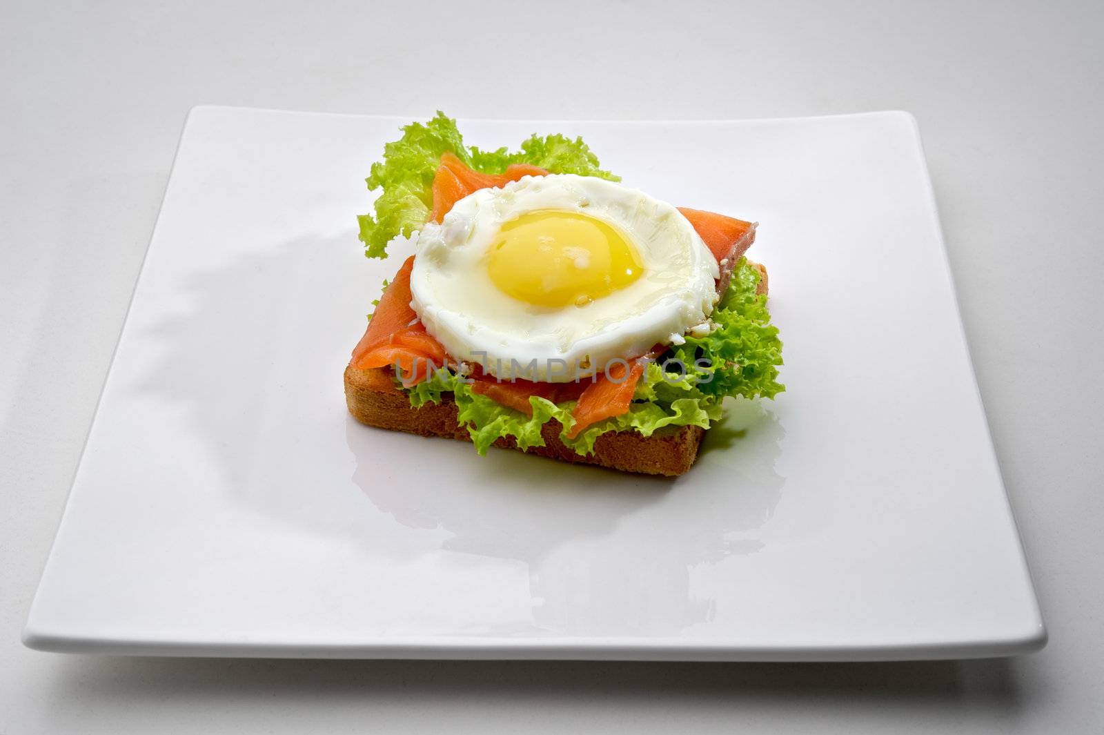 Fish breakfast with scrambled eggs and smoked salmon on toast, served on white plate