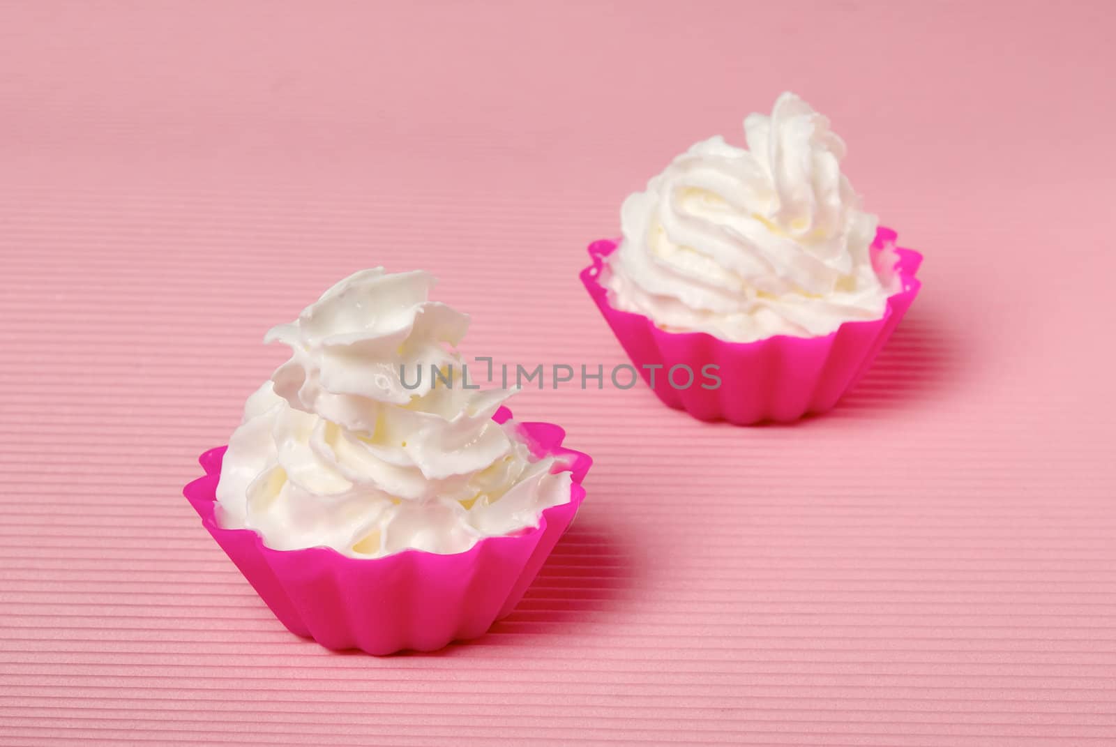 Two portions of whipped cream over pink background. Shallow DOF