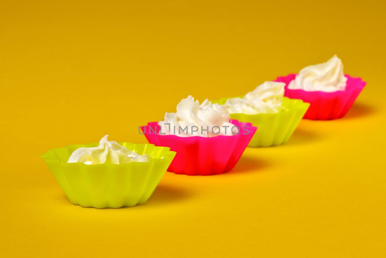 Four portions of whipped cream over yellow background. 