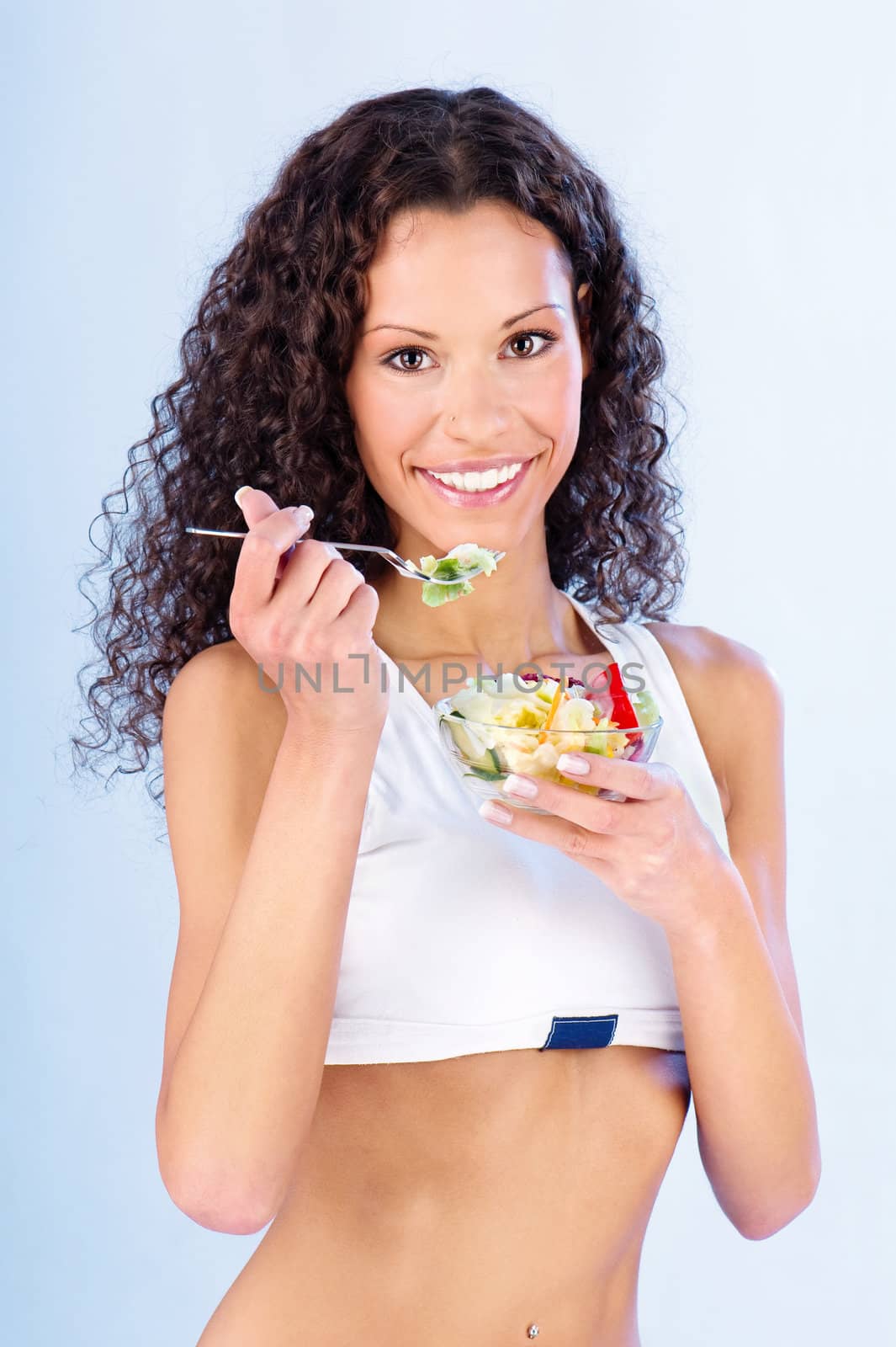 Pretty fitness woman holding salad on fork and plate