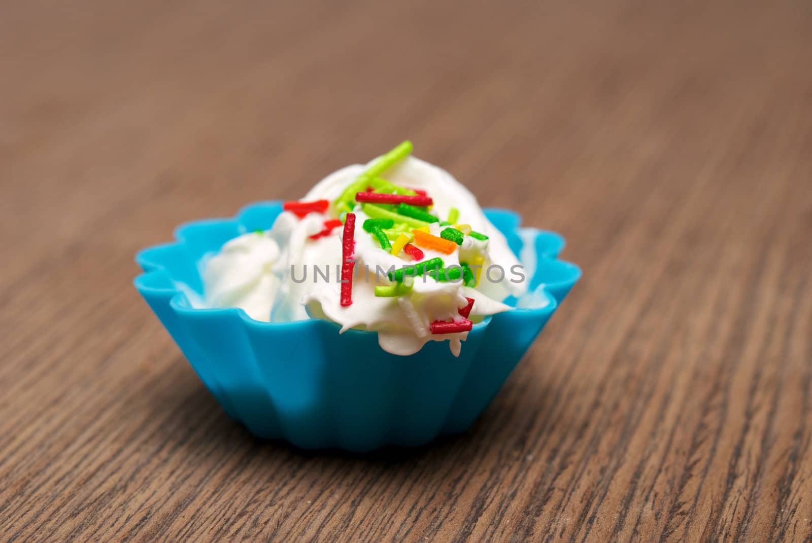 Portion of whipped cream in a blue form over wooden background. Shallow DOF