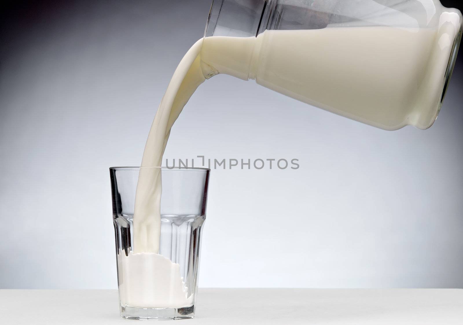 Pouring a glass of milk with splash from jug 