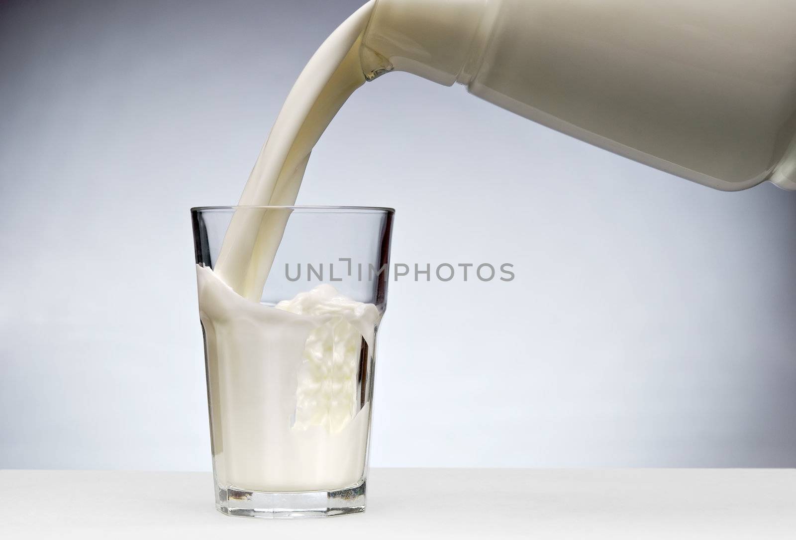 Pouring a glass of milk with splash from jug 