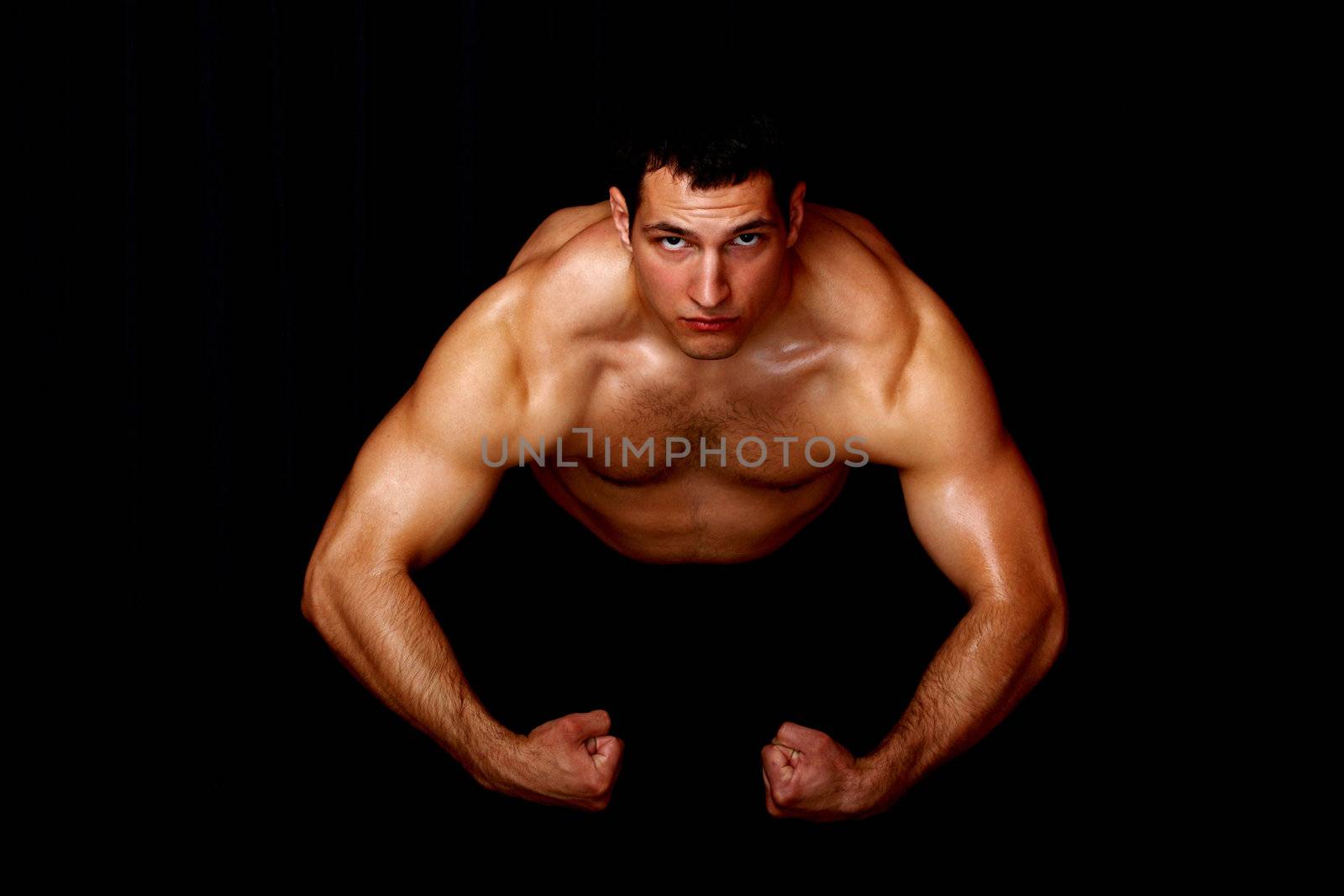 bodybuilder showing his strength, on black background
