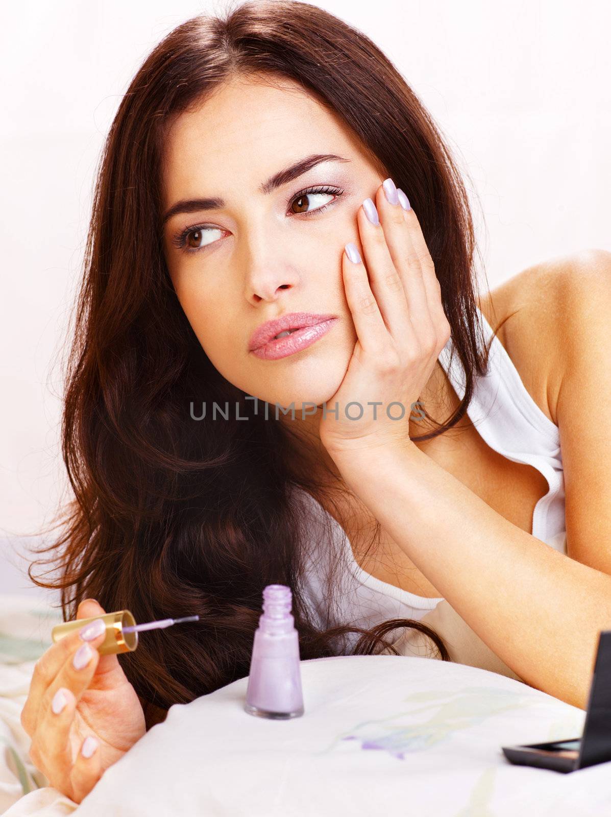 Pretty woman in bed  applying nail polish