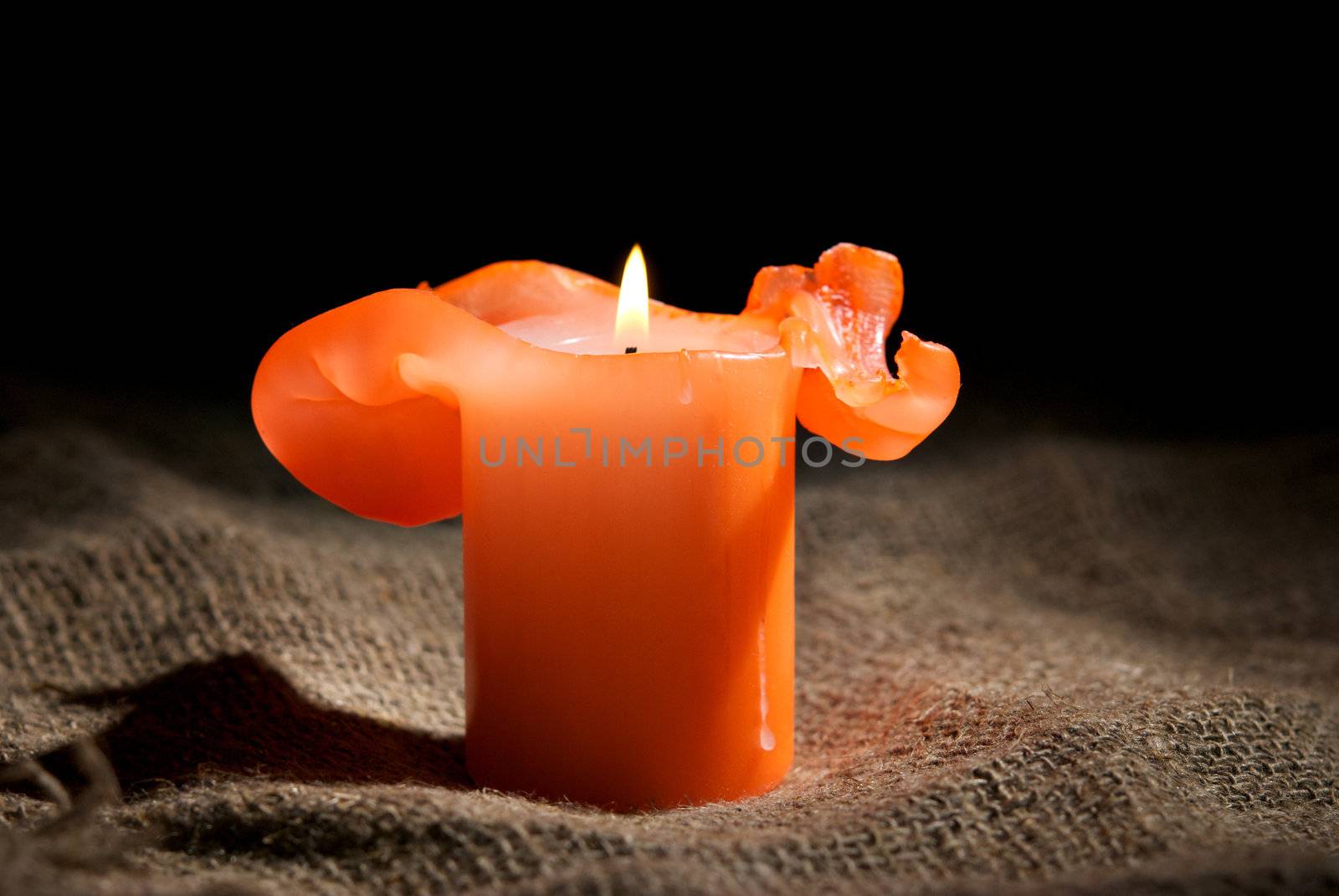 Closeup of a burning candle on the dark background