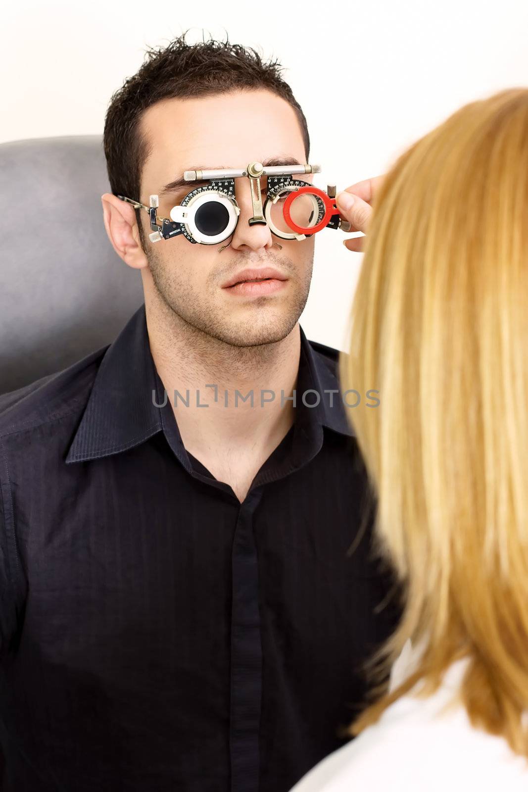 Male patient on medical attendance at the optometrist, wearing trial frame for eye testing