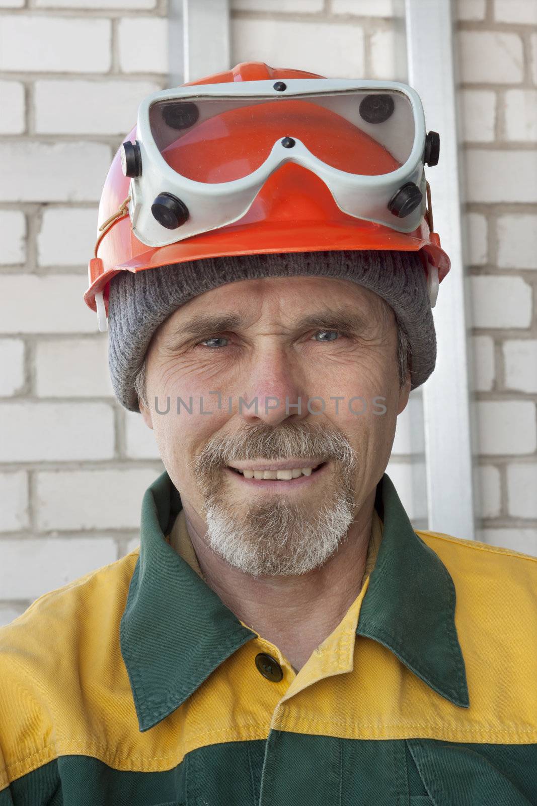 An elderly worker with spectacles and a protective helmet