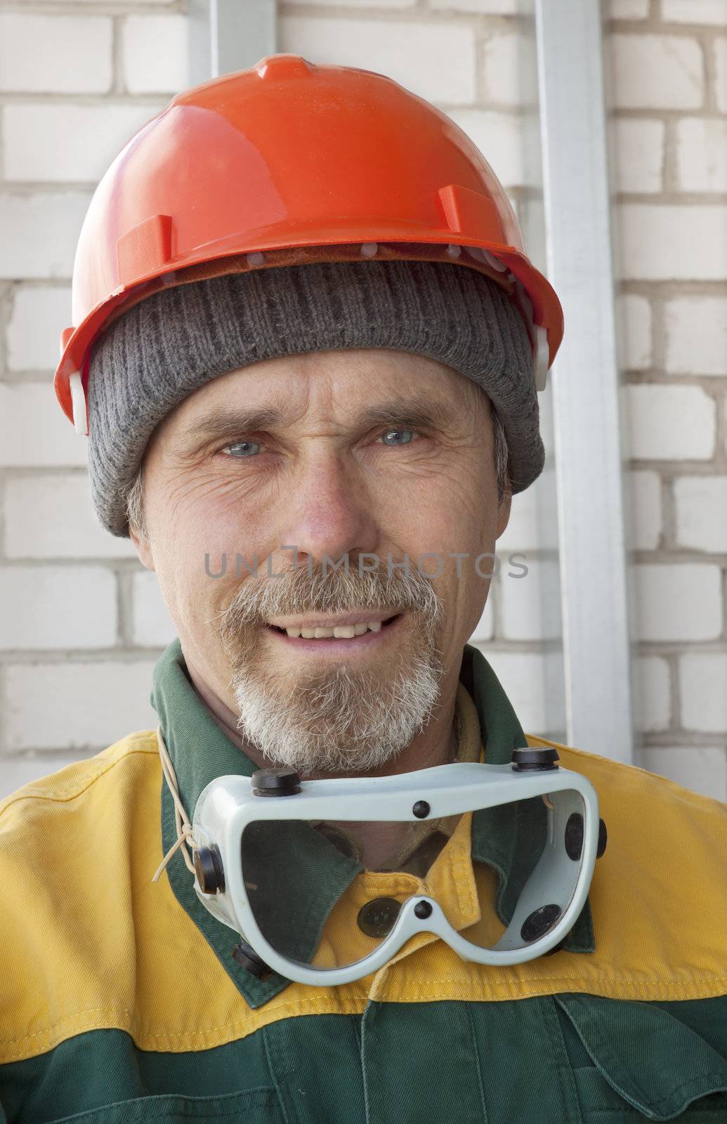 An elderly worker with spectacles and a protective helmet