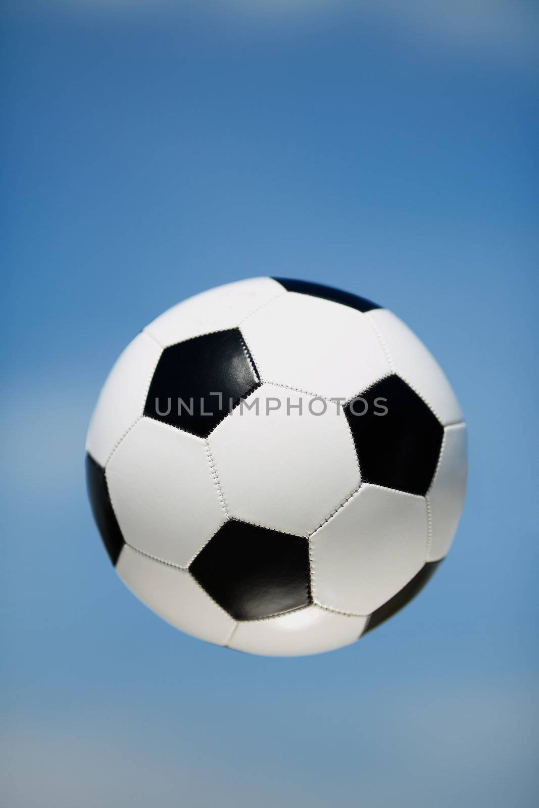 soccer ball on the blue sky background, selective focus on nearest part of ball