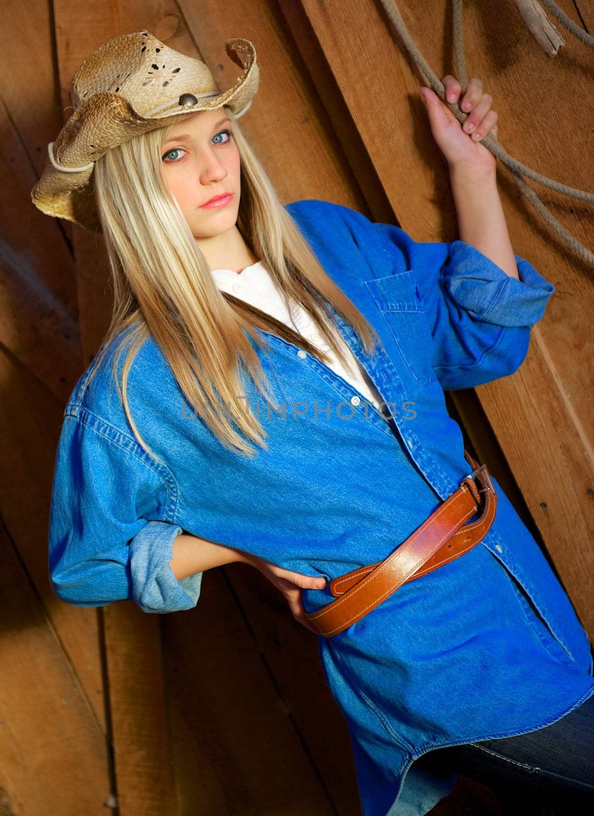 Beautiful, blond, teen model looks pensive as she wears a leather belt