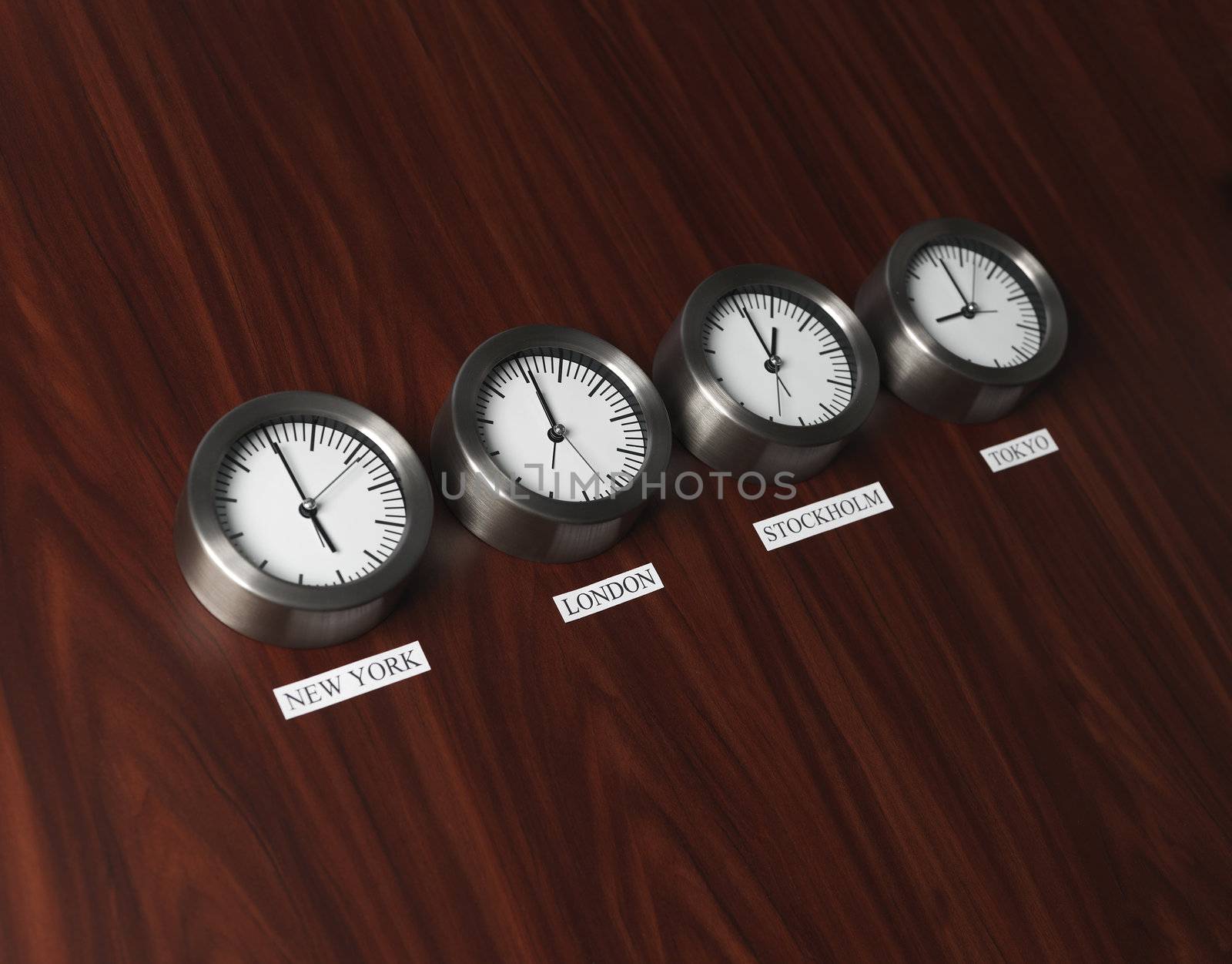 Four clocks with different time on Teak background