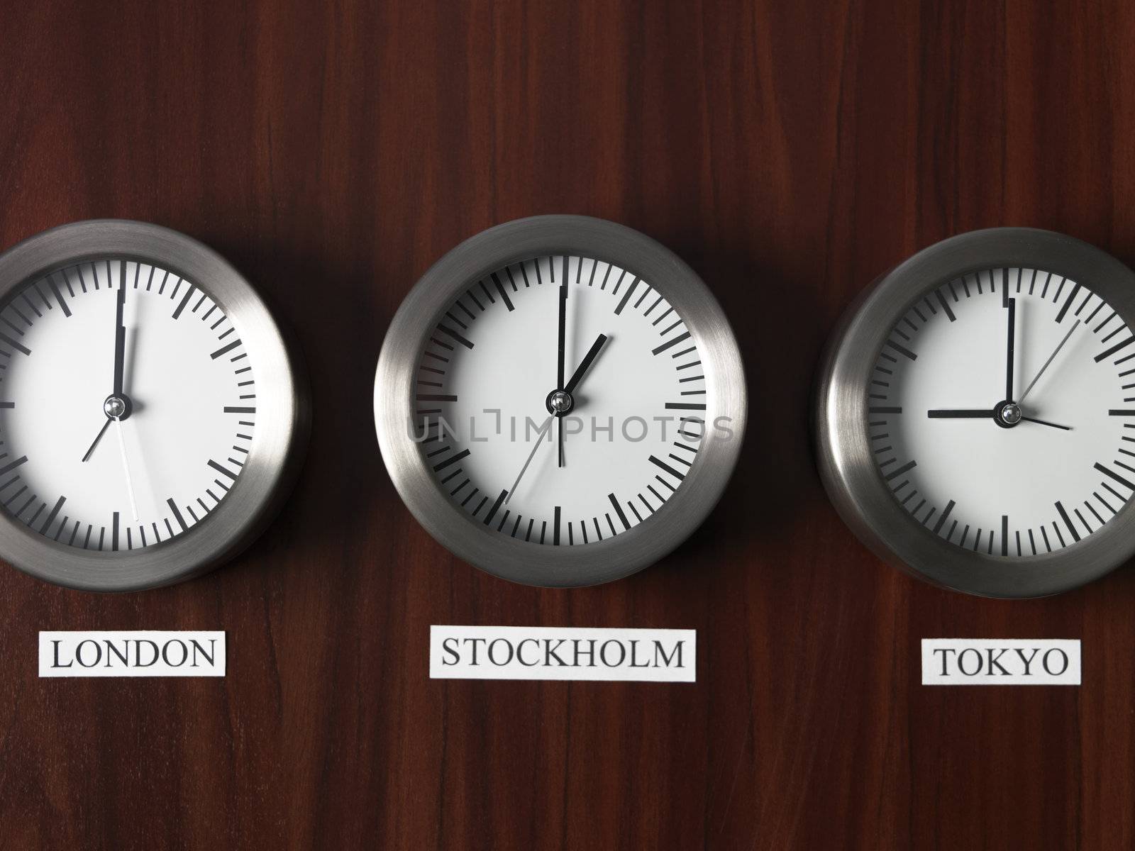 Three clocks with different time on Teak background