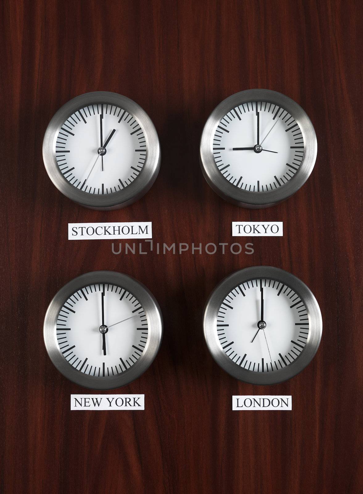 Four clocks with different time on Teak background