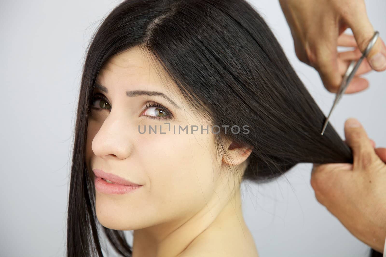 Female model with worried expression because her hair is being cut by hairdresser