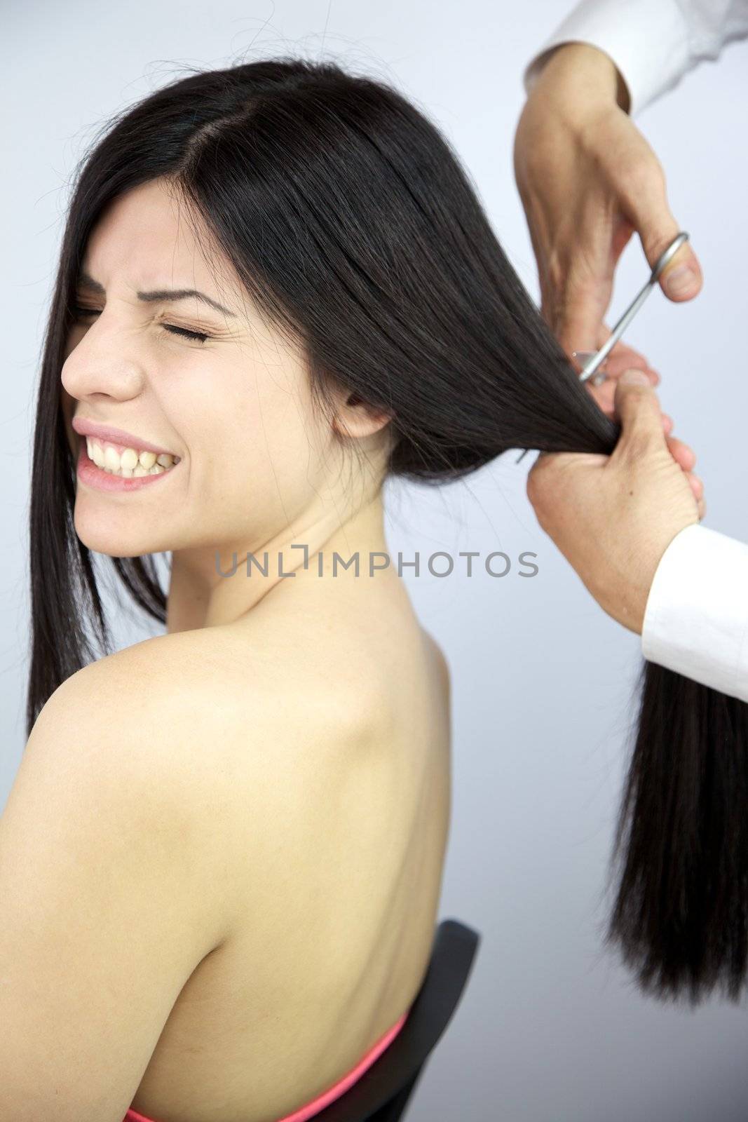 Beautiful woman closing eyes while hairdresser cuts her long hair by fmarsicano