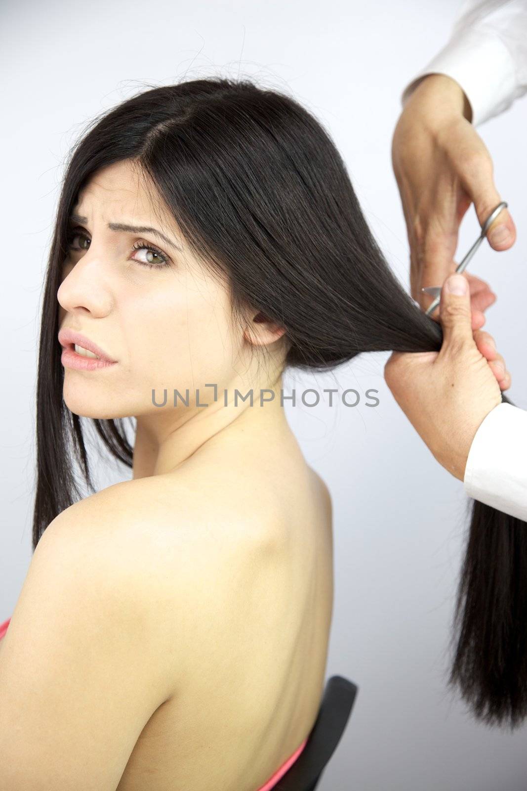 Hairdresser cutting long ponytail of gorgeous female model