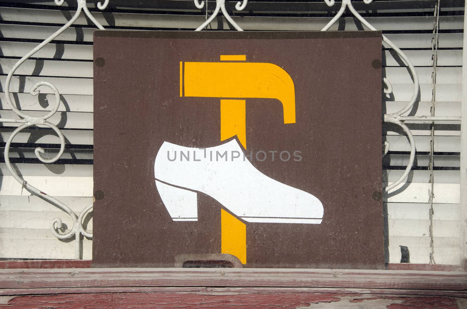 Shoe repair shop sign on window. Yellow hammer and white shoe.