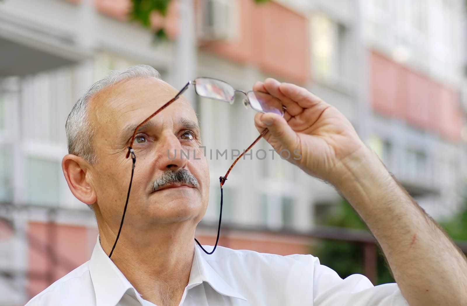 portrait of caucasian mature man looking up at his glasses