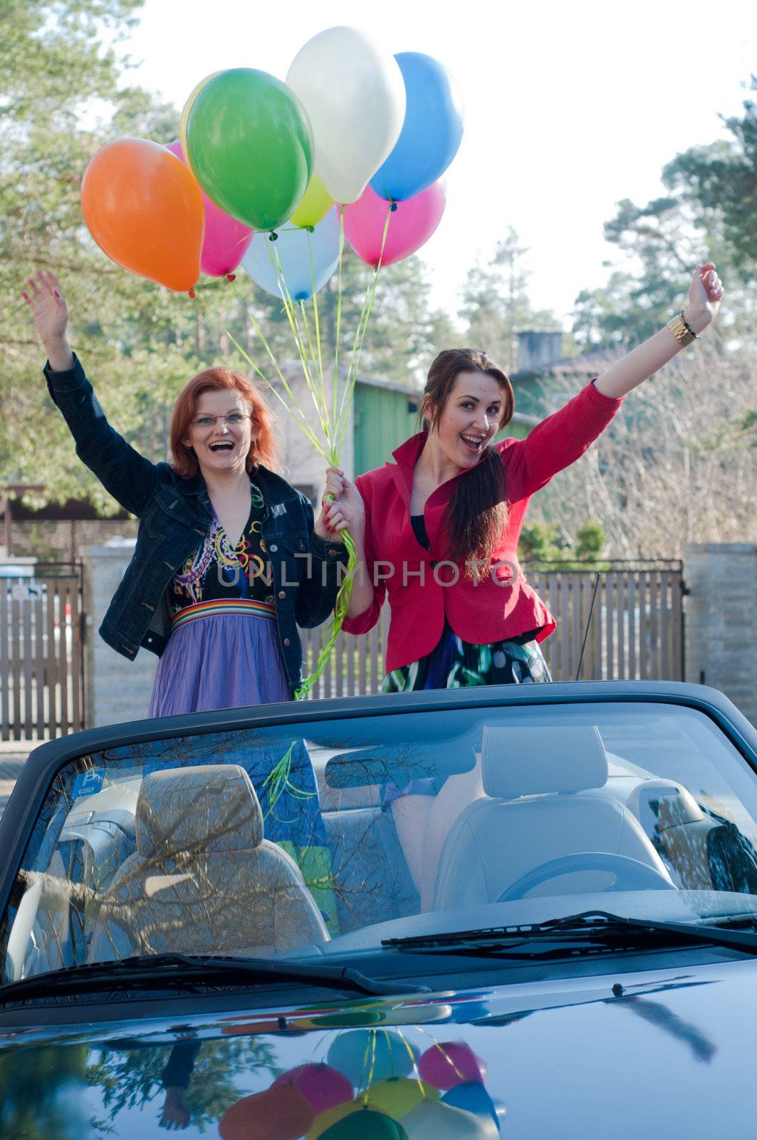 Two young happy girls with air balloons in cabrio, summer-spring time