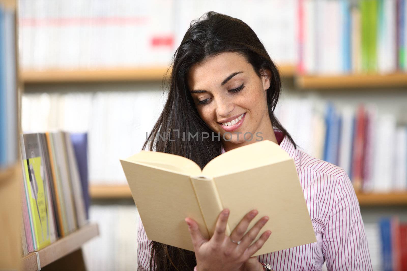 smiling female student with book in hands in a bookstore