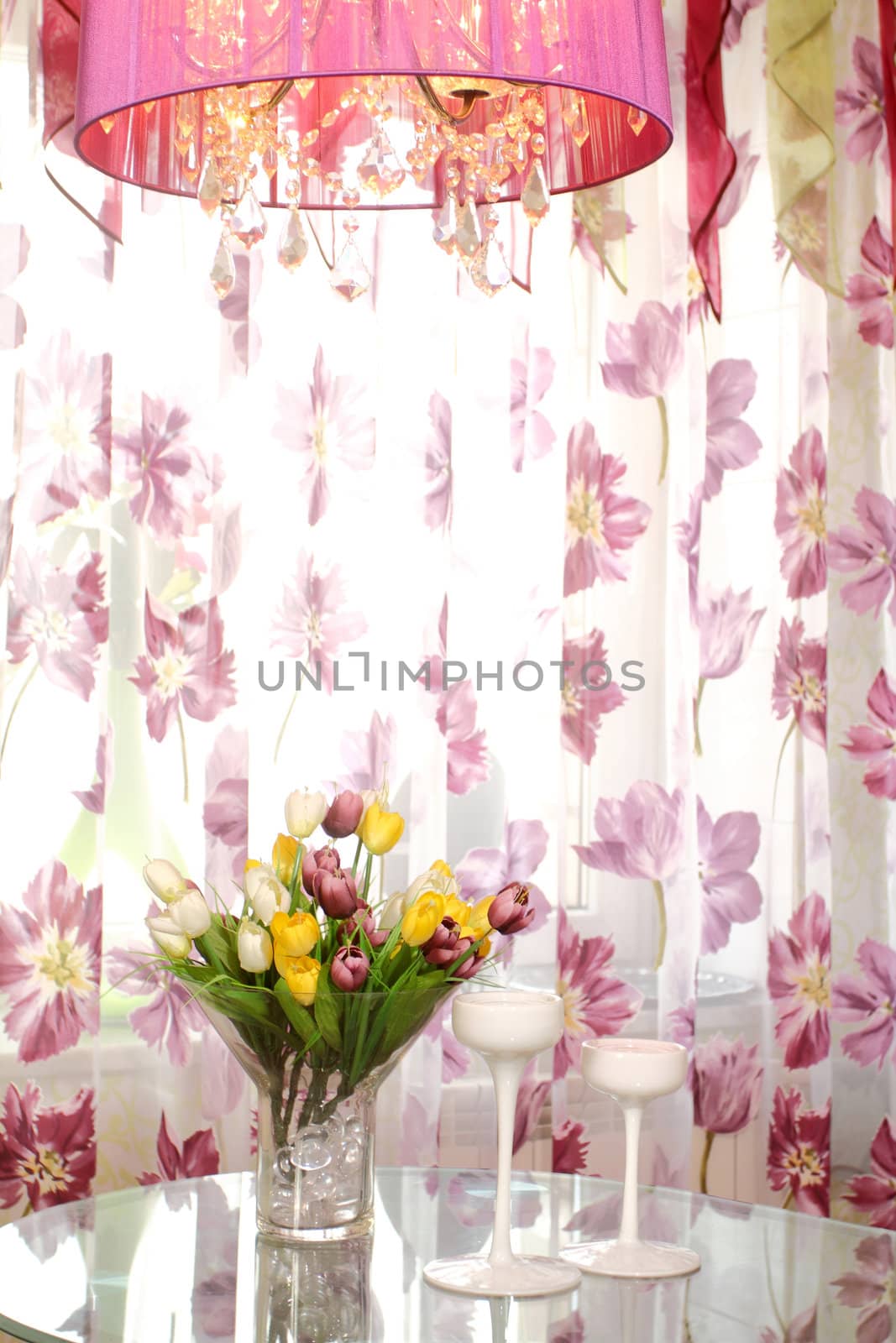 bouquet of multi-colored tulips on a glass table in a glass vase against a window, a vertical shot