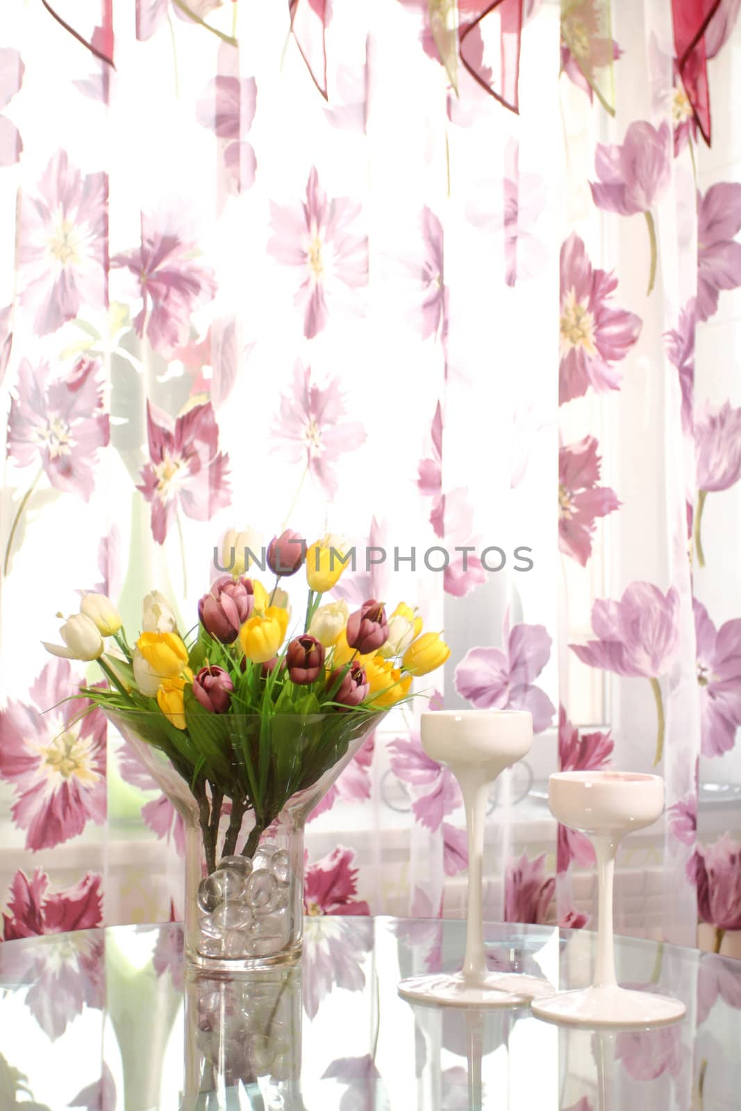 bouquet of multi-colored tulips on a glass table in a glass vase, a vertical shot