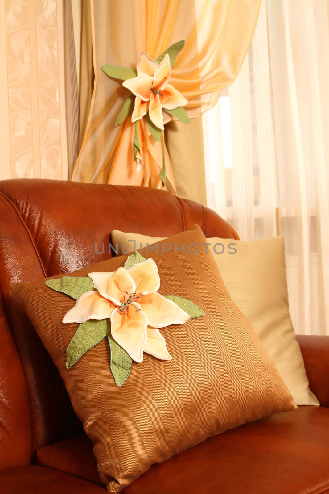 Brown leather sofa with beautiful pillows. Vertical shot, close up. The embroidery isn't a handiwork, this repetition of drawing on wall-paper.