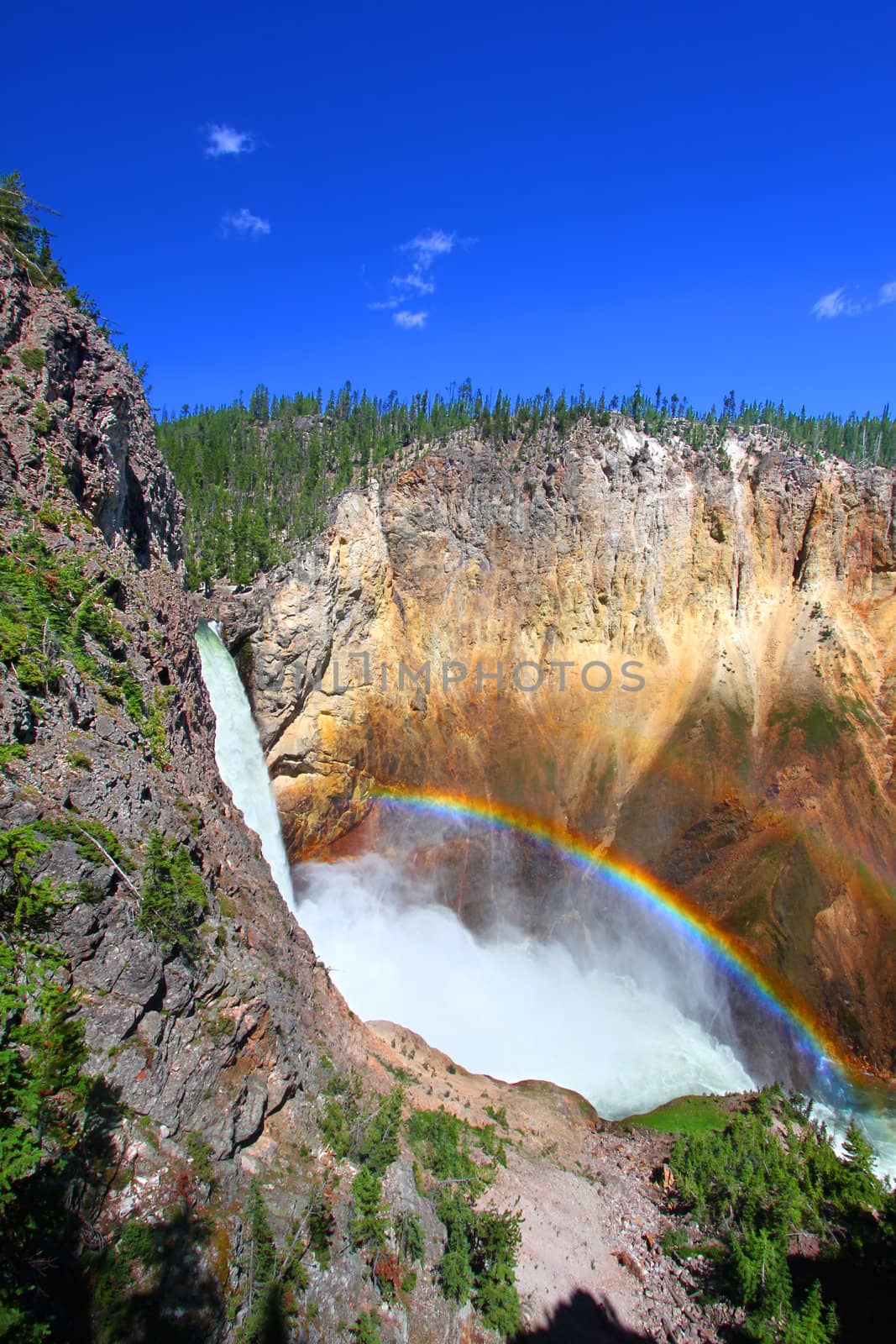 Sunlight creates a rainbow in mists of the Lower Falls of the Yellowstone River in Wyoming.