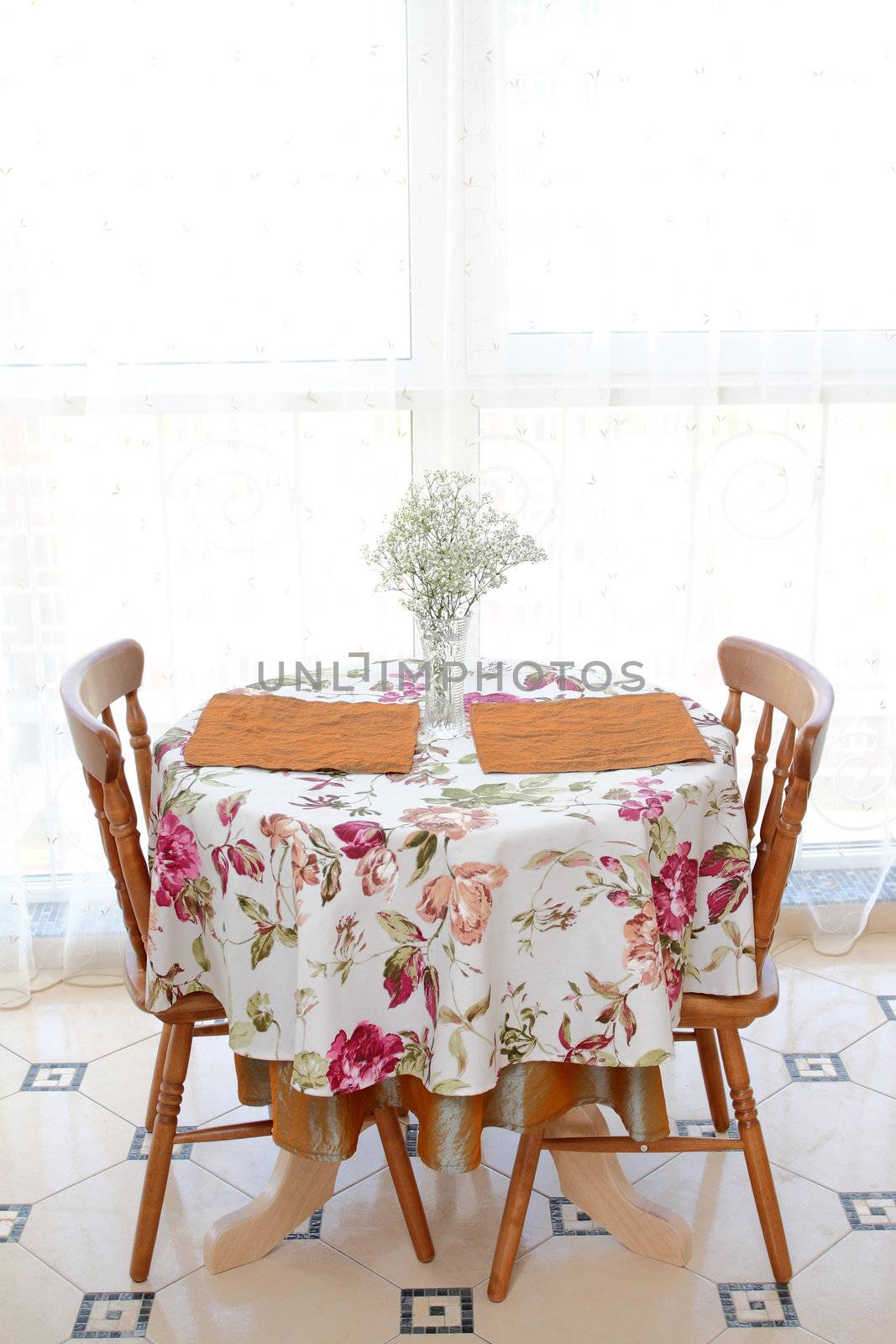 interior of the modern apartment, table with a bunch of flowers, two chairs against a big window, a vertical shot