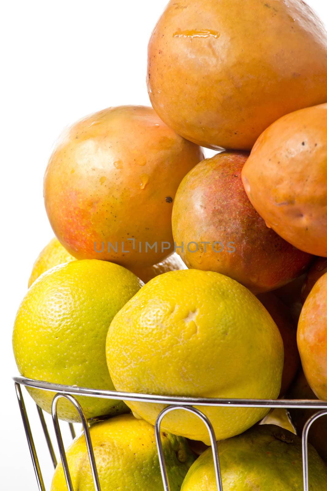 Delicious ripe oranges and mangoes piled up in a silver fruit bowl