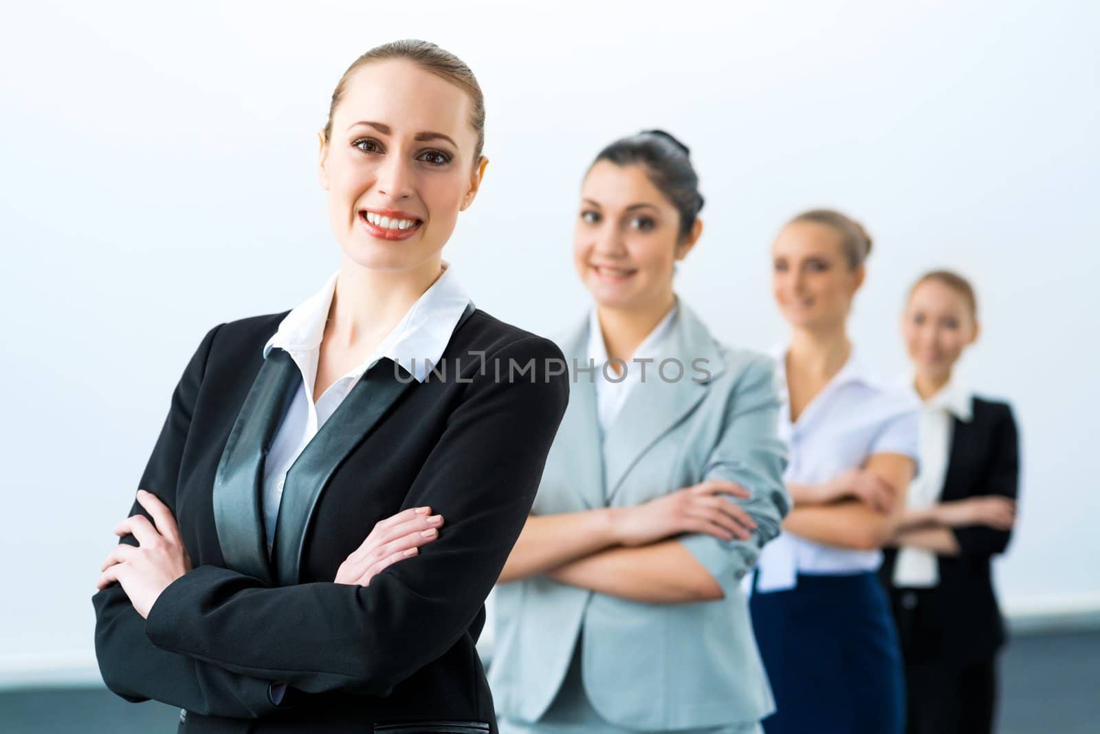 group of business people standing in a row, smiling and crossing his arms