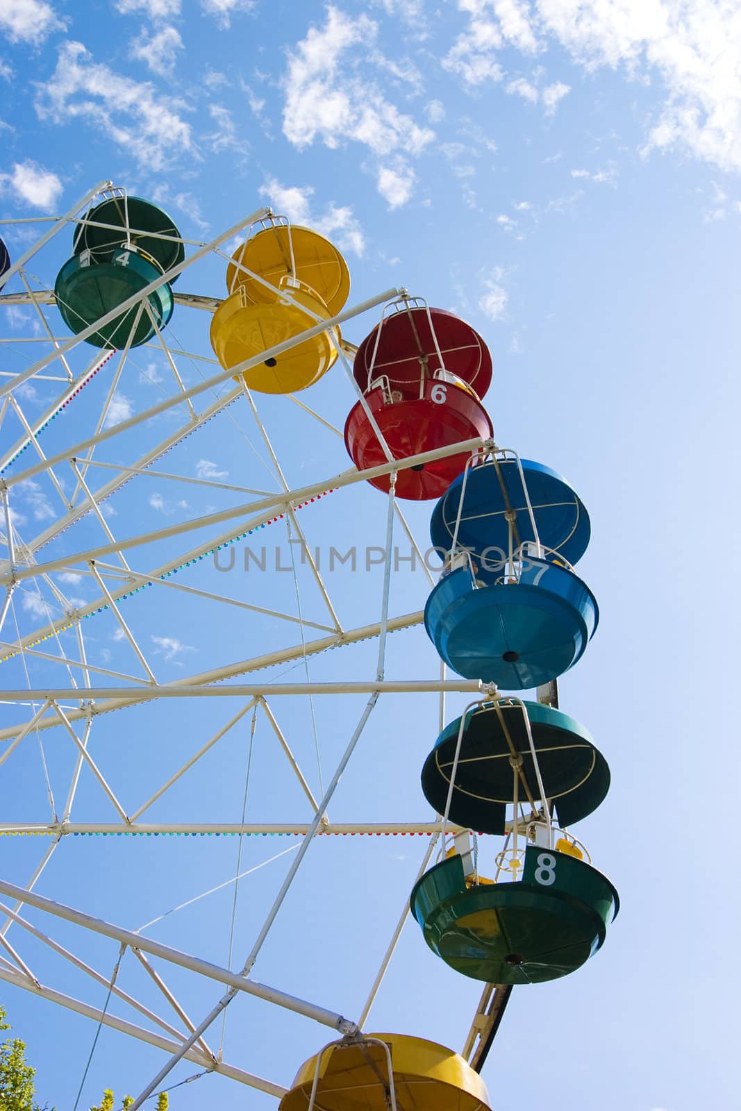 Popular attraction in park - a Ferris wheel on a background of the cloudy blue sky