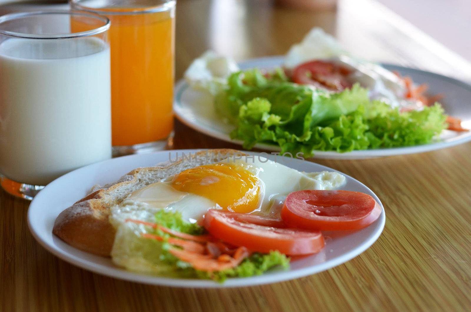 american style breakfast , with toast,  fried egg and fresh vegetables , milk and orange juice