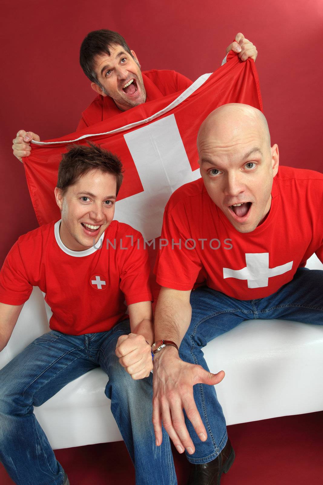 Photo of three male Swiss sports fans cheering for their team.
