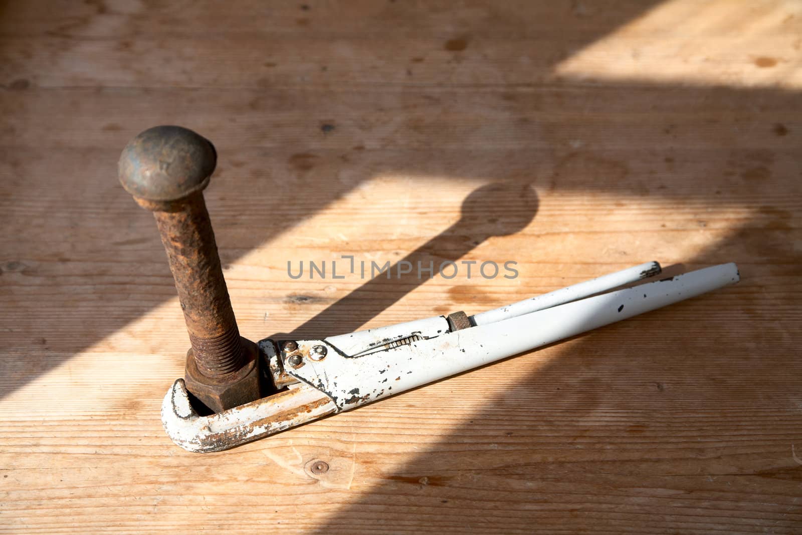 Adjustable spanner and rusty bolt with a nut on  wooden table