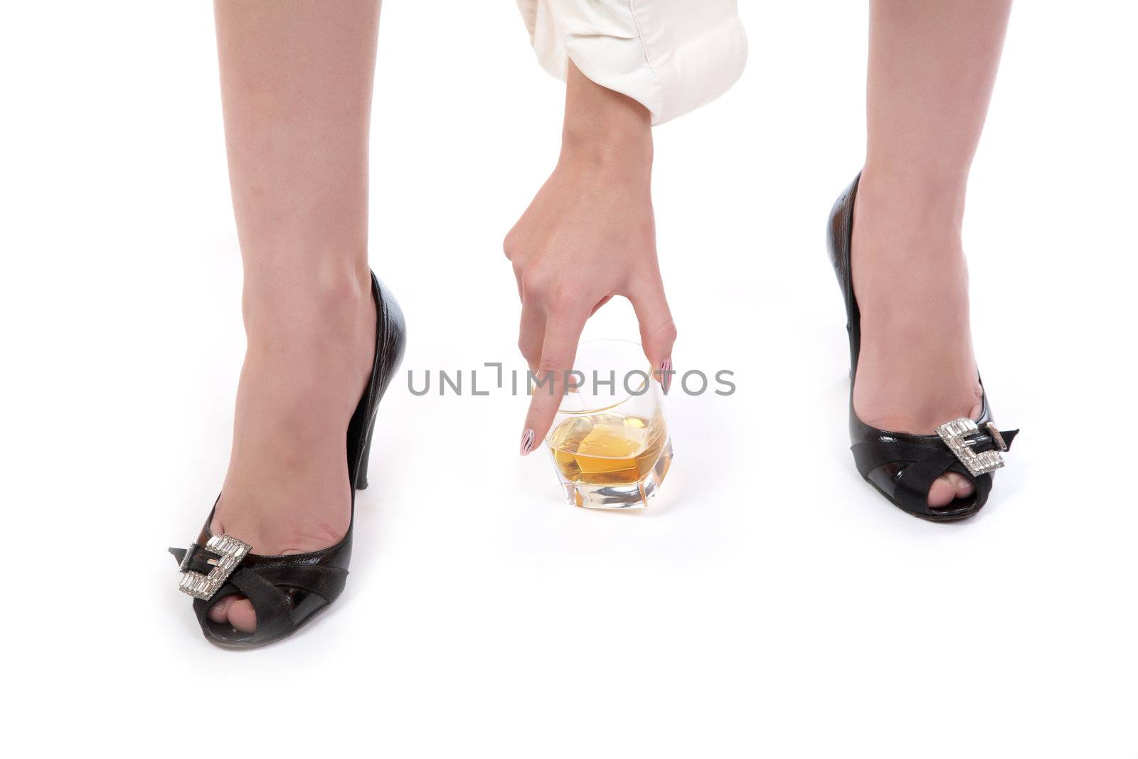 The hand of the girl puts a glass from whisky on a floor