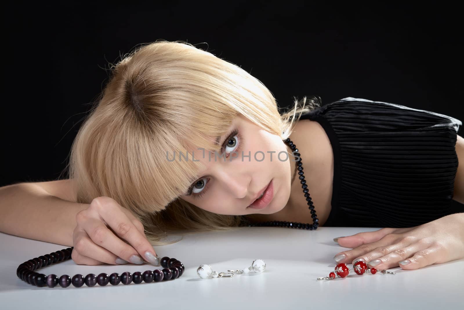 The girl with beads from pearls in a hand on black background