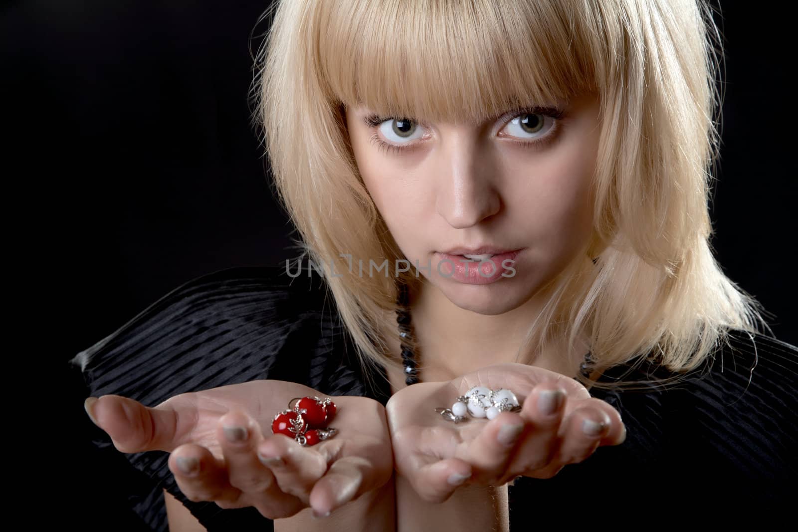 The girl with earrings in hands on a black background
