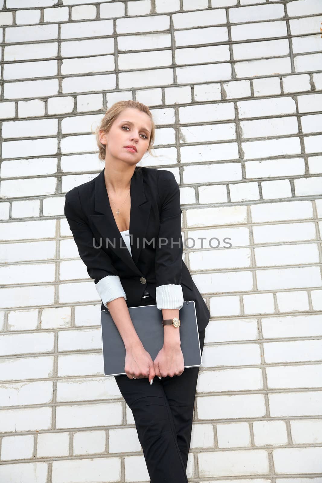 girl in  business suit and with the laptop against  wall from a brick