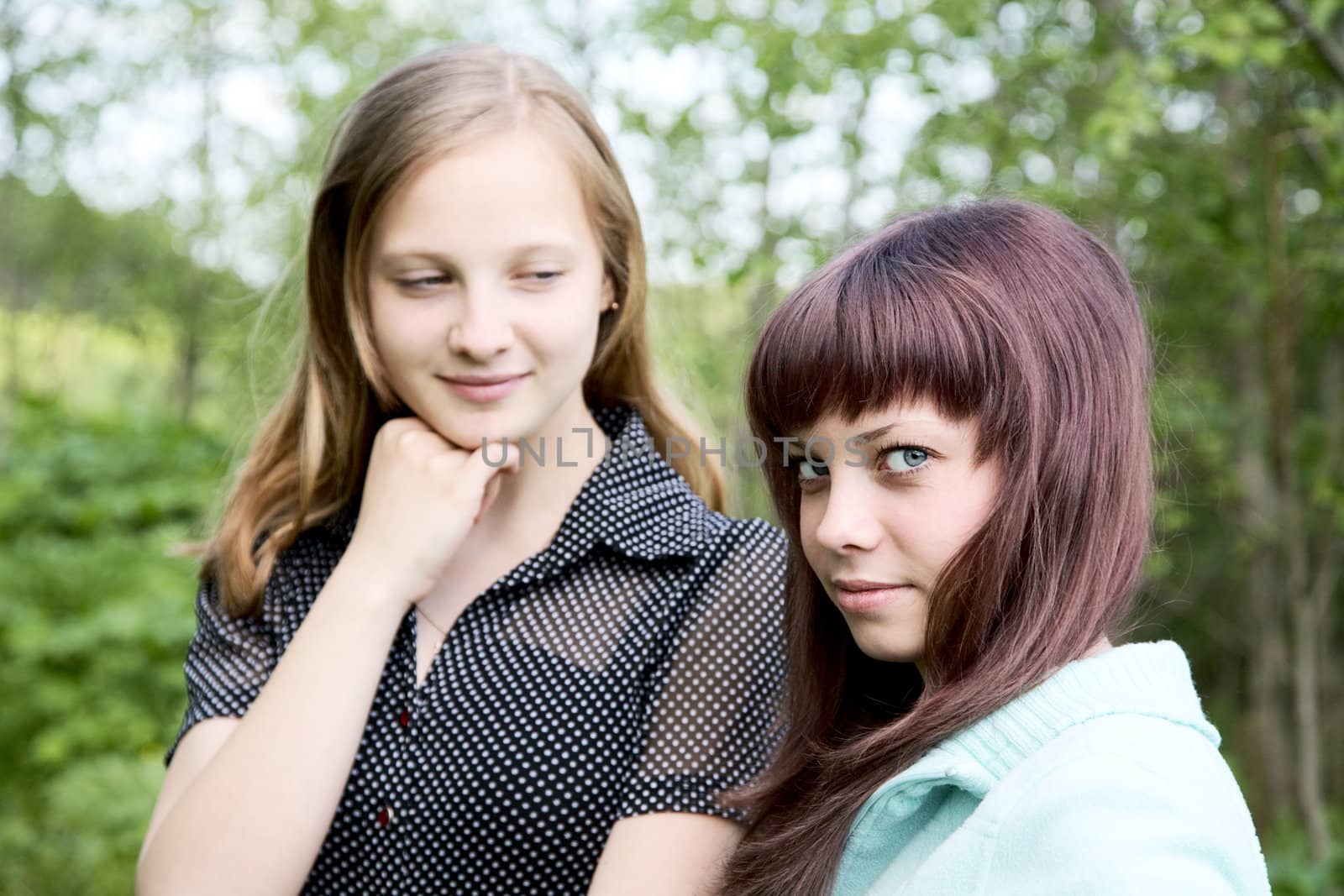 Two girls of the teenager in  spring afternoon against green foliage