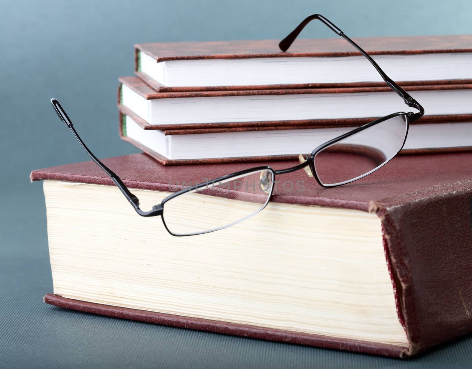 Pile of books and glasses on old thick volume
