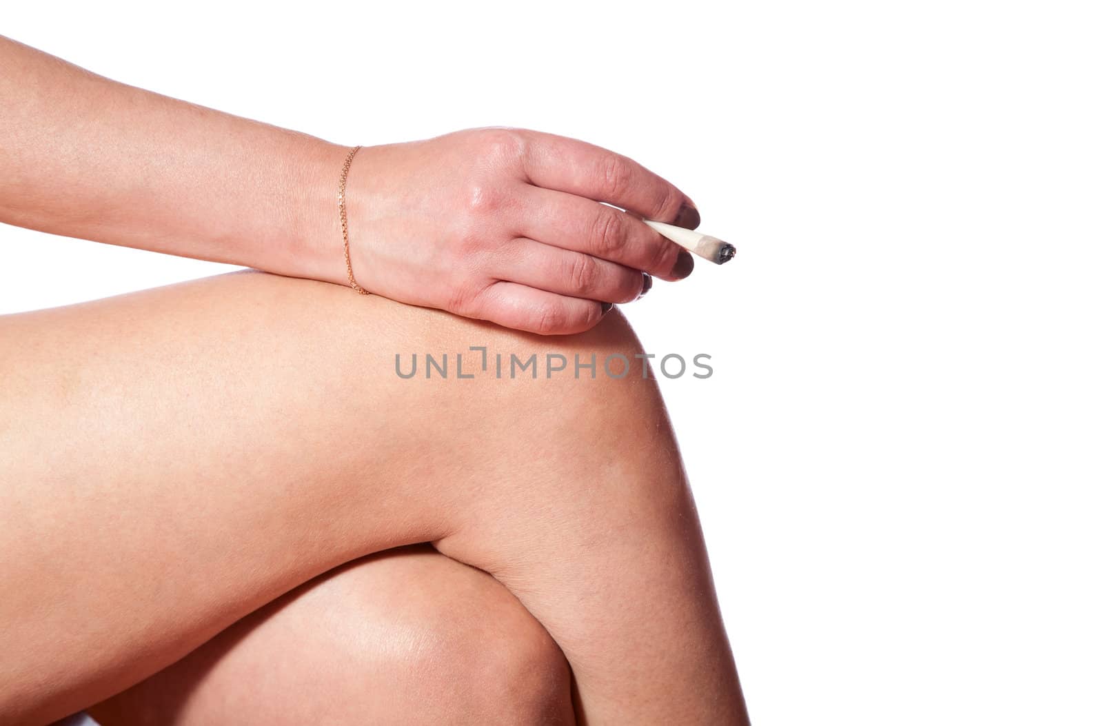 Female hand with  cigarette on  knee  white background